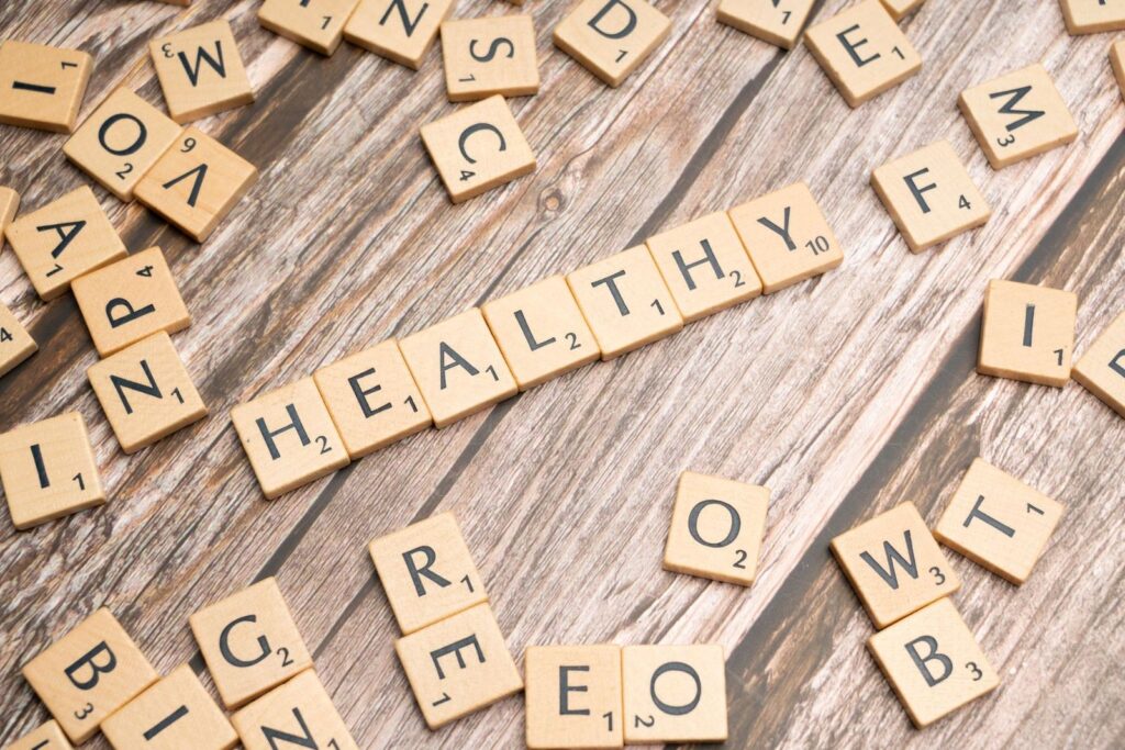Wooden letter tiles arranged on a wooden surface spelling out 'healthy', symbolizing wellness.