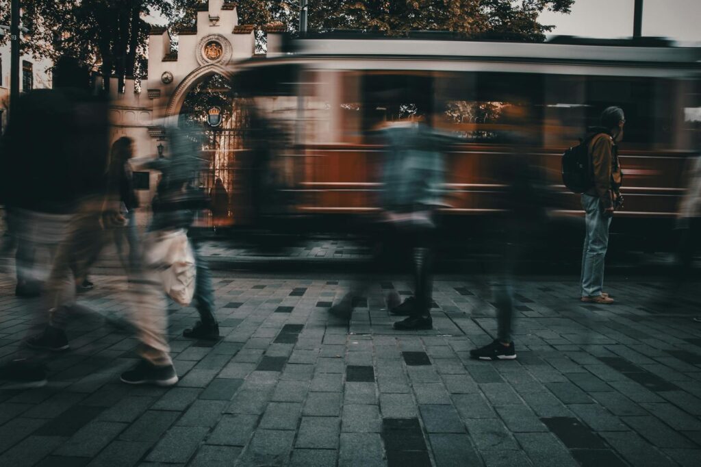Blurred unrecognizable pedestrians walking on paved street near aged tramway in motion in old city