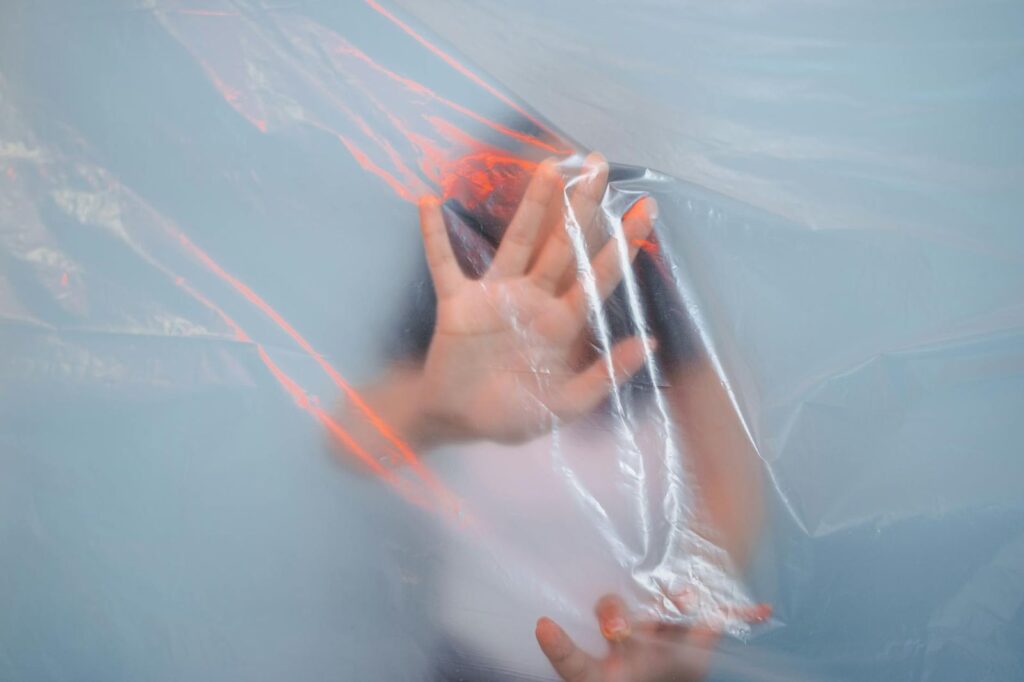 Human hand pressing against clear plastic sheet, creating a unique visual effect.